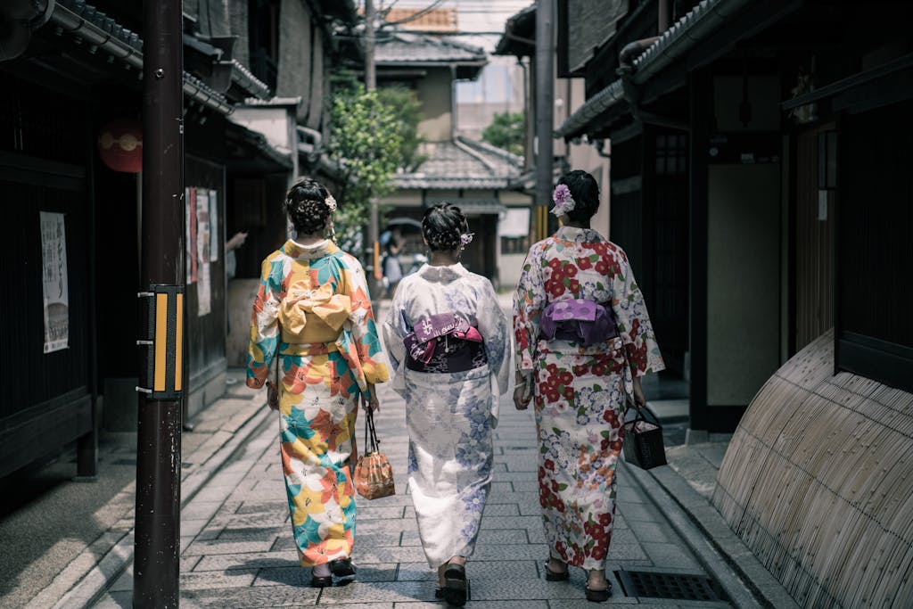 Three women in colorful kimonos walking through a traditional street in Kyoto, Japan.